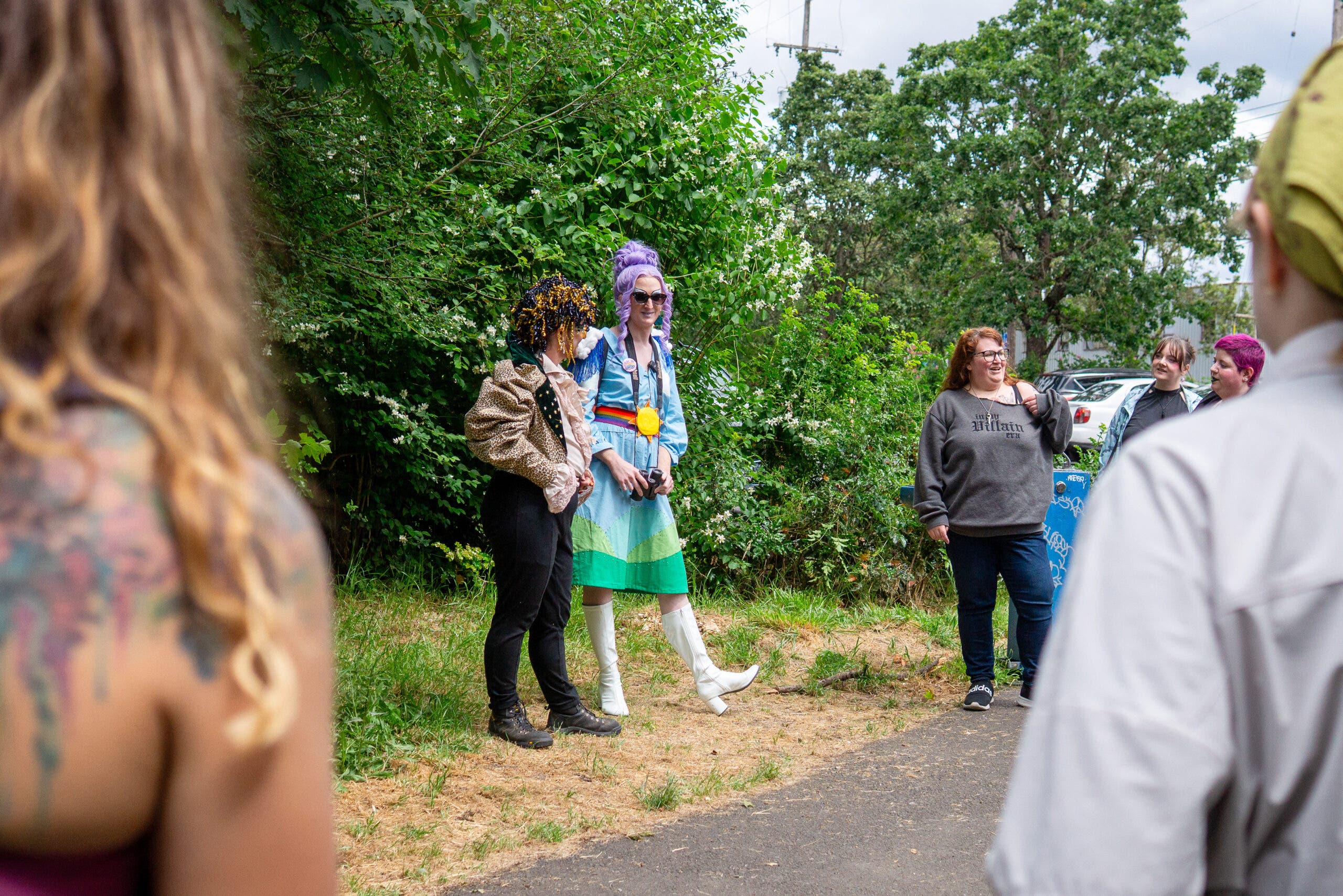 Hosp and Skye are pictured in full glam alongside a trail, speaking in front of other urban hikers